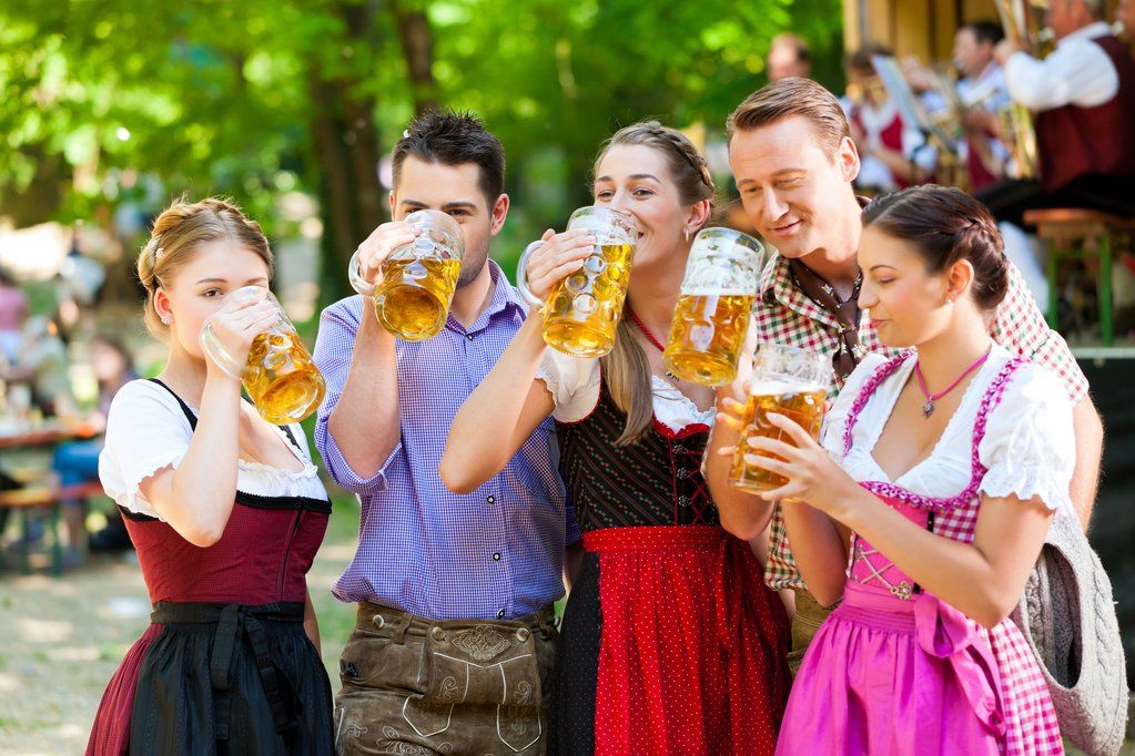 Gruppe junger Männer und Frauen in Tracht stößt mit Bierkrügen auf dem Oktoberfest 2025 in München an.