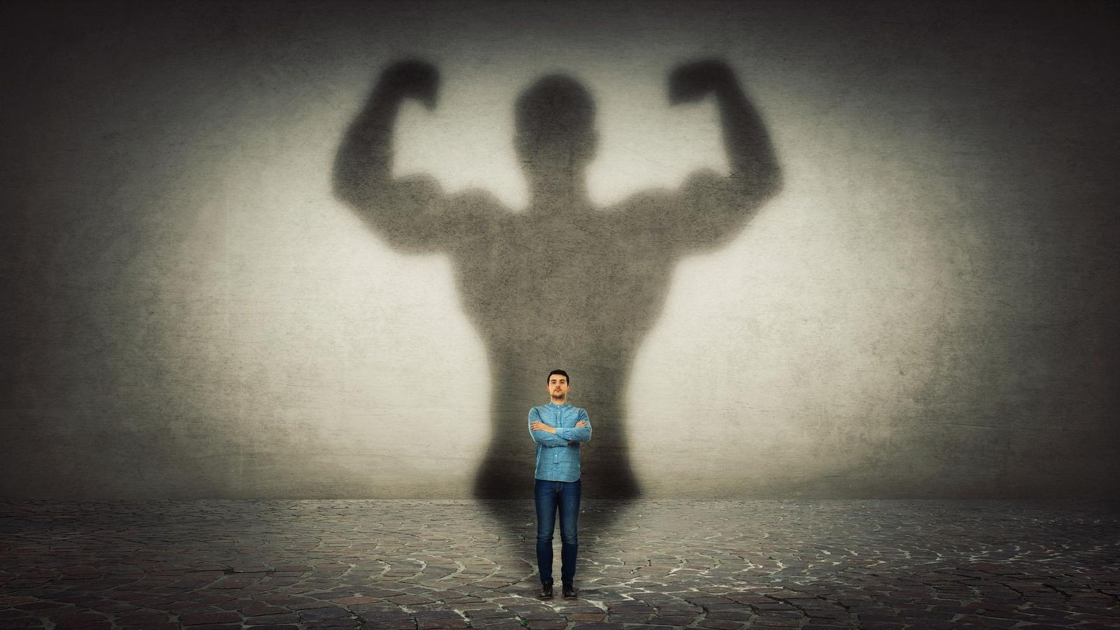 Ein kleiner Mann stand selbstbewusst da. Sein mächtiger Schatten fiel an die Wand.