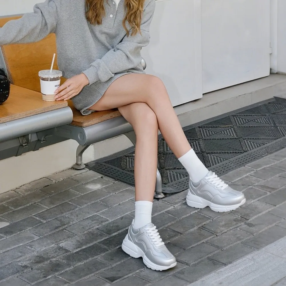 Eine Frau in Chamaripa-Sneakers sitzt entspannt im Park.
